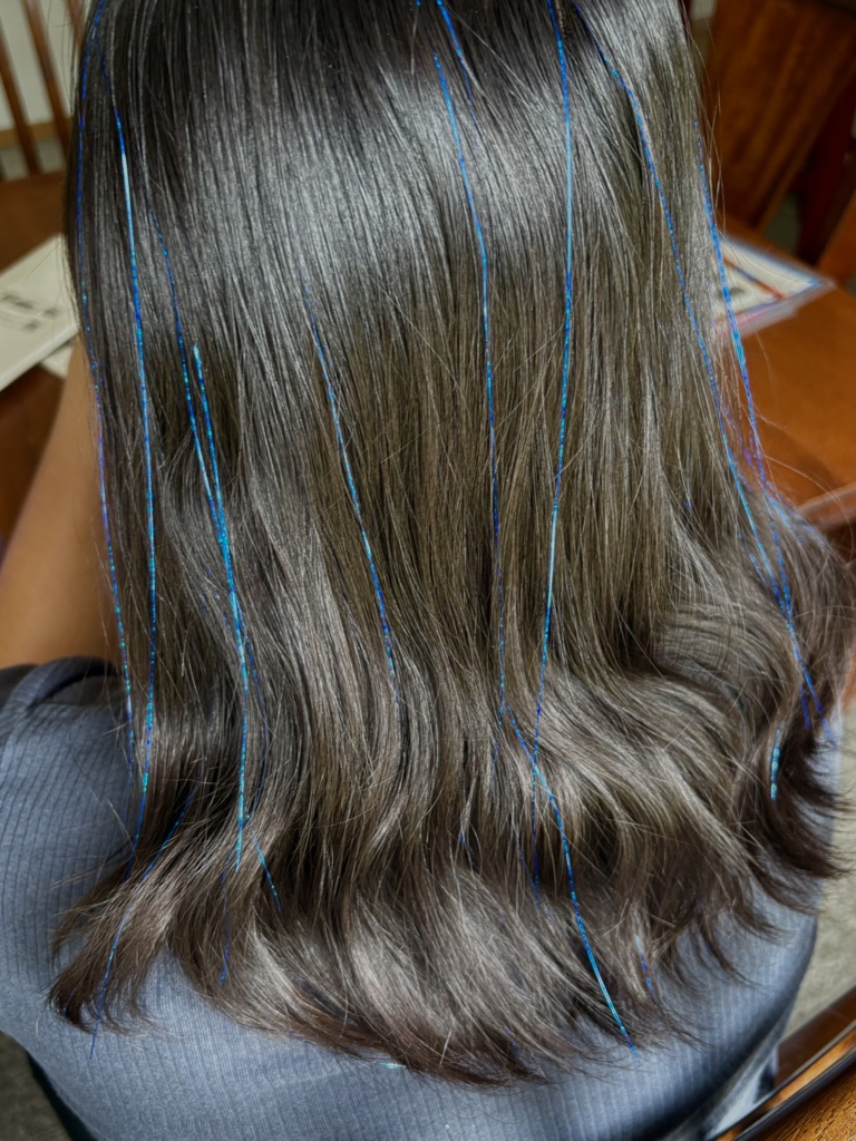 The child's blue tinsel hair strands are made of sparkly strands that give the appearance of flowing strands of hair that ...